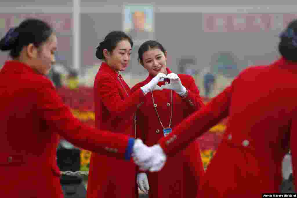 Ushers pose for photos in Tiananmen Square during the opening of the 19th National Congress of the Communist Party of China in Beijing. (Reuters/Ahmad Masood)