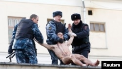 Police detain Pyotr Pavlensky after he cut off part of his earlobe.