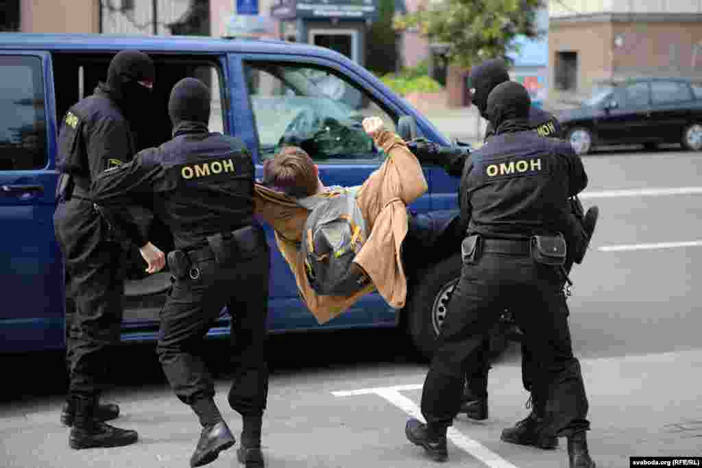 A student is detained and carried into a van by police.