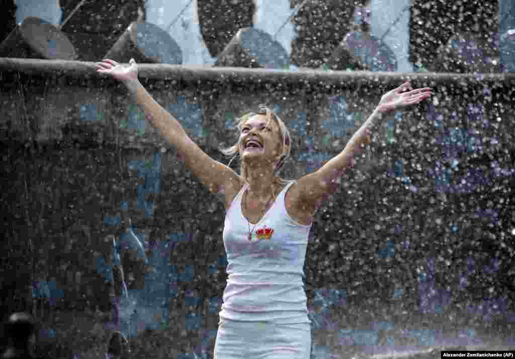 A woman cools off in a fountain in the Alexander Garden near the Kremlin Wall in Moscow, Russia. (AP/Alexander Zemlianichenko)