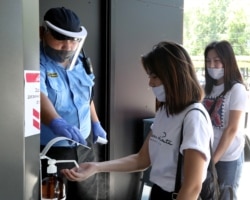 Посетители торгового центра в Бишкеке пользуются санитайзером для обработки рук.