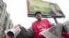 A Communist Party activist holds flyers for State Duma candidates in front of a Yabloko campaign poster in Moscow on December 2, two days before the voting.