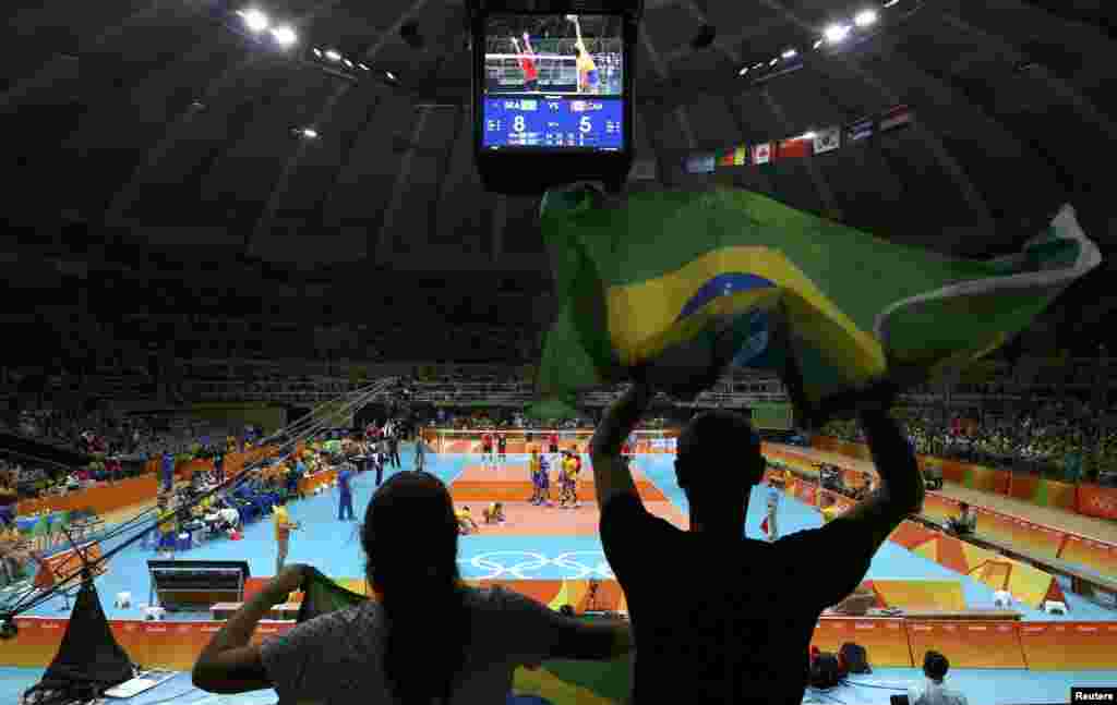 Supporters hold Brazilian flags during their country's volleyball game against Canada.