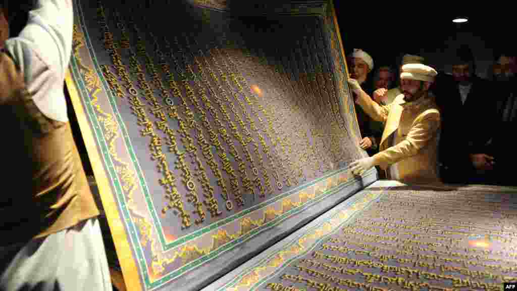 Nj&euml; artist afgan dhe student&euml;t e tij shfaqin nj&euml; faqe t&euml; madhe nga Kurani, n&euml; ceremonin&euml; e hapjes s&euml; Bibliotek&euml;s Naser Khusro Balkhi n&euml; Kabul m&euml; 12 janar. (AFP / Shan Marai)