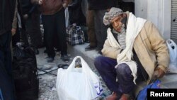 An elderly civilian sits with his belongings as he waits to be evacuated from a besieged area of Homs on February 7.