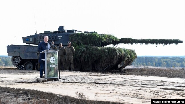 Germaniya kancleri Olaf Şol'c "Leopard 2" tankisiniñ janında söylep twr. 17 qazan 2022 jıl.