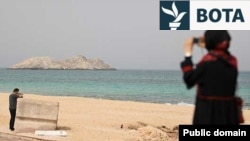 Një grua fotografon detin nga ishulli Abu Musa, në Gjirin Persik. Fotografi nga arkivi. 