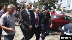 Police escort former Kosovo Central Bank Governor Hashim Rexhepi (second left) after his arrest in Pristina last year. 