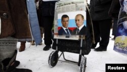 Фотографии президента России Владимира Путина и премьер-министра Дмитрия Медведева, прикрепленные к коляске одного из участников митинга в знак протеста против принятия "закона Димы Яковлева". Санкт-Петербург, 13 января 2013 года.