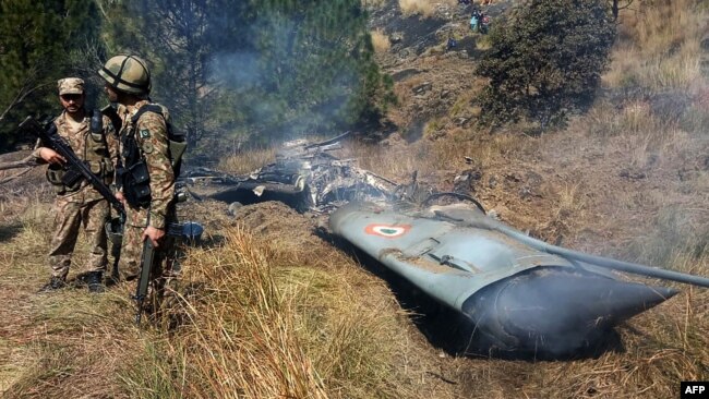 Pakistani soldiers stand next to the wreckage of an Indian fighter jet shot down in Pakistan-controlled Kashmir on February 27.