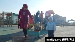 Женщина с детьми рядом с детской площадкой в микрорайоне в Шымкенте. 2 марта 2014 года.