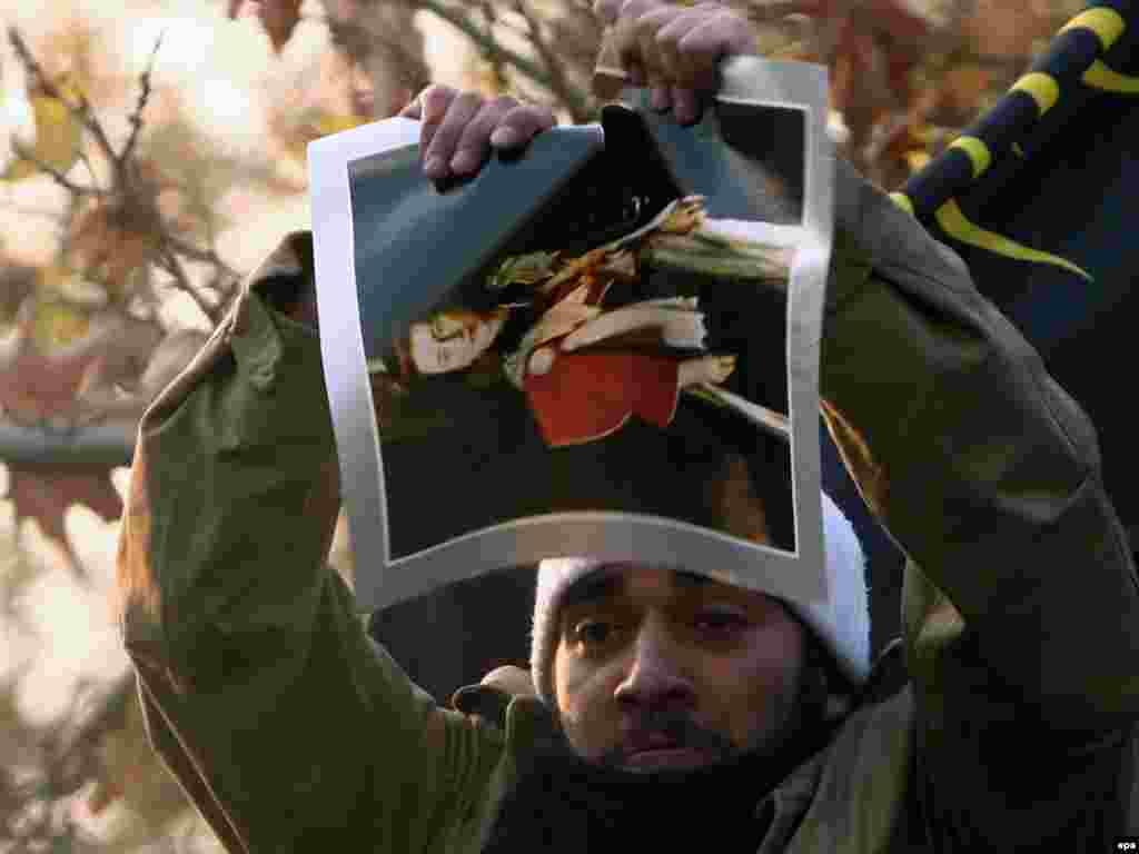 A man tears a picture of Queen Elizabeth II that was taken from the British Embassy compound in Tehran on November 29. (EPA/Abedin Taherkenareh)