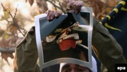 A protester tears up a picture of Queen Elizabeth II taken from inside the British Embassy in Tehran.