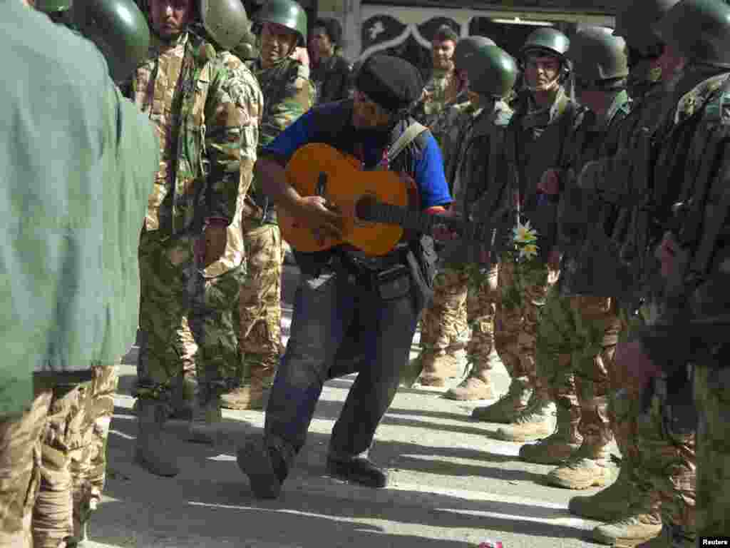 A protester plays his guitar among Kurdish security forces during a demonstration in Sulaimaniya.