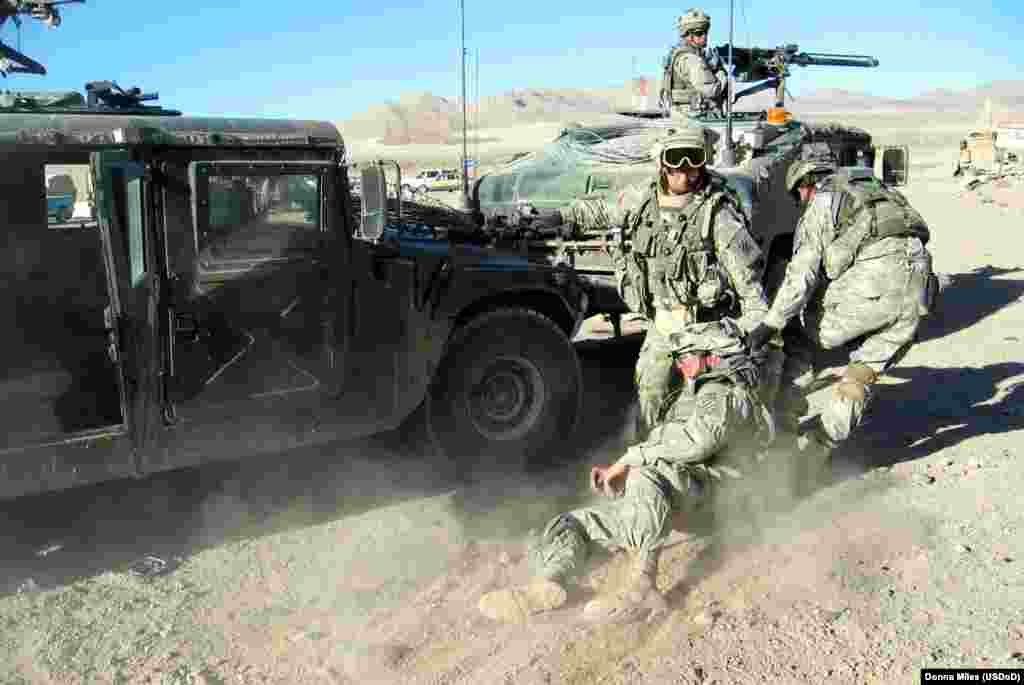 Army medics pull a &quot;wounded&quot; comrade to a Humvee after a simulated IED attack.&nbsp;