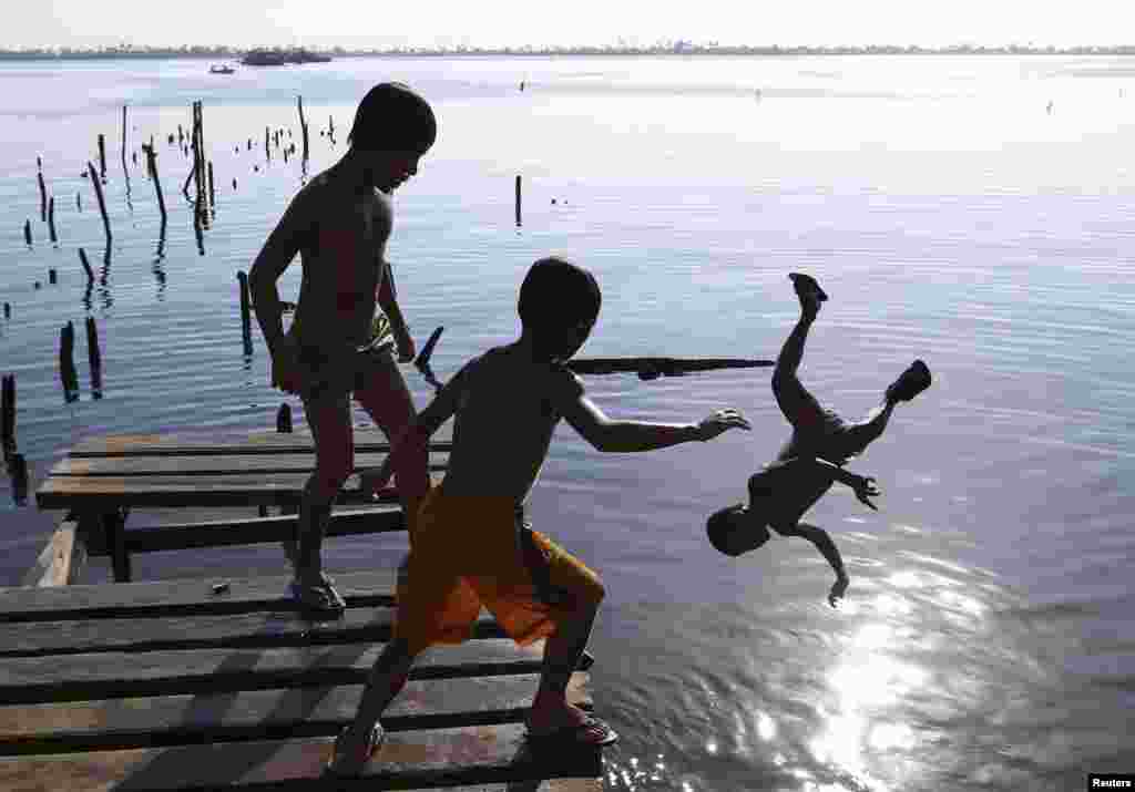 Boys jump from a foot bridge damaged by Typhoon Haiyan in the central Philippines. Almost 25,000 people still live in tents, shelters, and bunkhouses in the hardest hit regions. (Reuters/Erik De Castro)