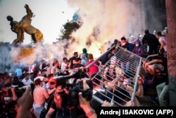 Protesters clash with police in front of Serbia's National Assembly building in Belgrade on July 8 during a demonstration against a weekend curfew announced to combat a resurgence of COVID-19 infections.