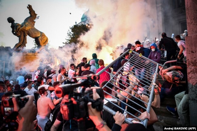 Protesters clash with police in front of Serbia's National Assembly building in Belgrade on July 8 during a demonstration against a weekend curfew announced to combat a resurgence of COVID-19 infections.