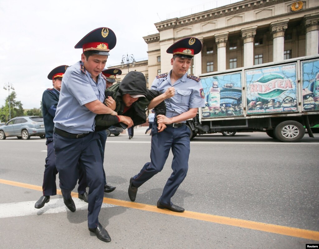 Polıeıler narazylyq akııasyna qatysýshyny kólikke kúshtep salýǵa ákele jatyr. Almaty, 10 maýsym 2019 jyl.