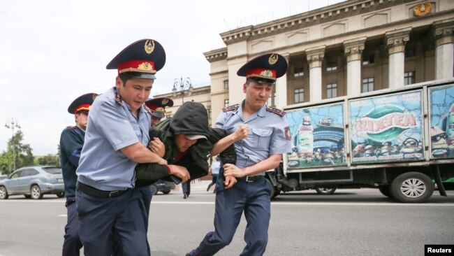 Полицейские несут задержанного на акции протеста в автозак. Алматы, 10 июня 2019 года.