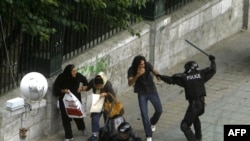 A riot police officer strikes a civilian during the violent crackdown at Tehran University one year ago. 