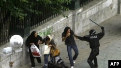 An Iranian riot-police officer attacks a man with a baton near Tehran University on June 14. Mir Hossein Musavi has urged his supporters to continue their protests in a "peaceful and legal way" and urged police to refrain from violence.