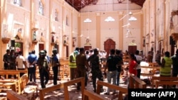 Sri Lankan security personnel walk through debris following an explosion in St Sebastian's Church in Negombo, north of the capital Colombo on April 21.