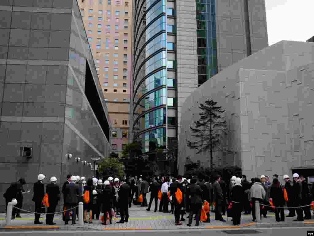 Japan--Companies employees stand outside of their offices after an earthquake hit Tokyo, 11Mar2011 - Сотрудники компаний эвакуированы из зданий после землетрясения. Токио, Япония, 11 марта 2011 года. EPA / FRANCK ROBICHON