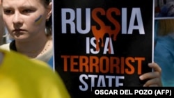 Молода українка з плакатом «Росія – держава-терорист» на акції під час саміту НАТО у столиці Іспанії. Мадрид, 29 червня 2022 року