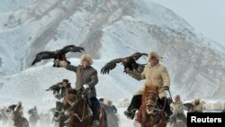 Herdsmen hold their falcons as they ride on horses during a hunting competition in Akqi county, Xinjiang Uyghur Autonomous Region.