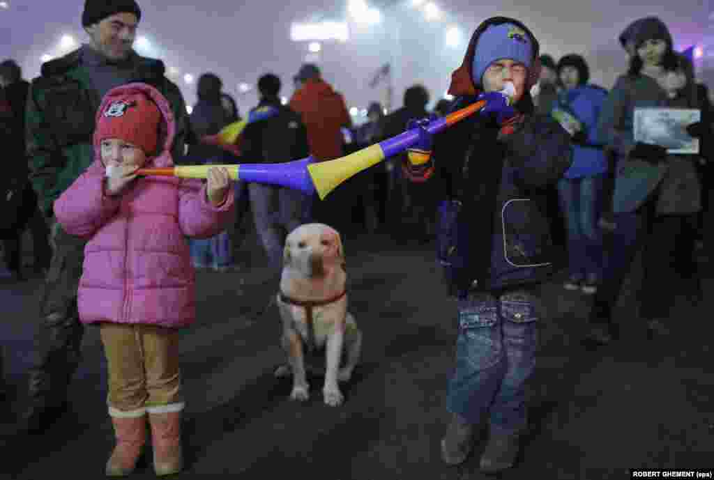 Two Romanian children play toy trumpets during an antigovernment demonstration in front of government headquarters in Bucharest on February 6. (epa/Robert Ghement)