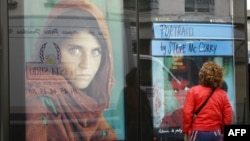 Paris. Küçədə fotoqraf Steve McCurry-nin çəkdiyi fotolara baxan qadın