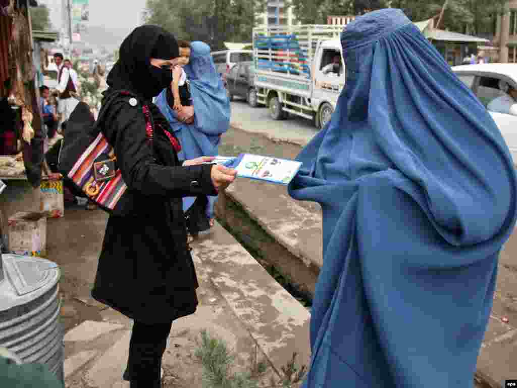 Afghanistan -- A woman distributes leaflets illustrating vote casting in Kabul, 03Aug2010