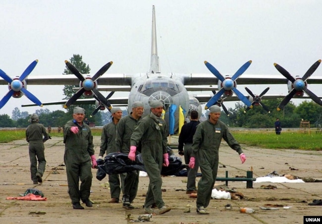 Офіцери українських військово-повітряних сил несуть тіло людини, яка загинула в результаті падіння винищувача