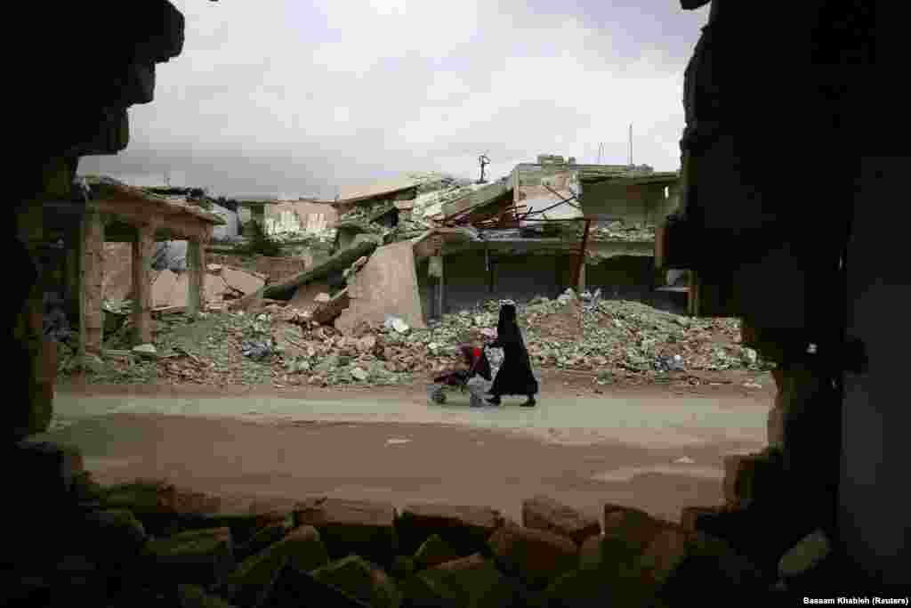 A woman pushes a baby trolley past damaged buildings in the rebel-held, besieged district of Douma in eastern Damascus, Syria. (Reuters/Bassam Khabieh)