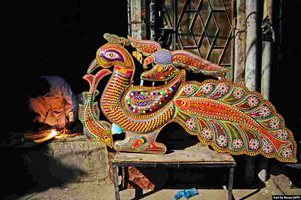 A welder in Rawalpindi works next to a completed decoration that will be mounted on the panel of a jingle truck. 