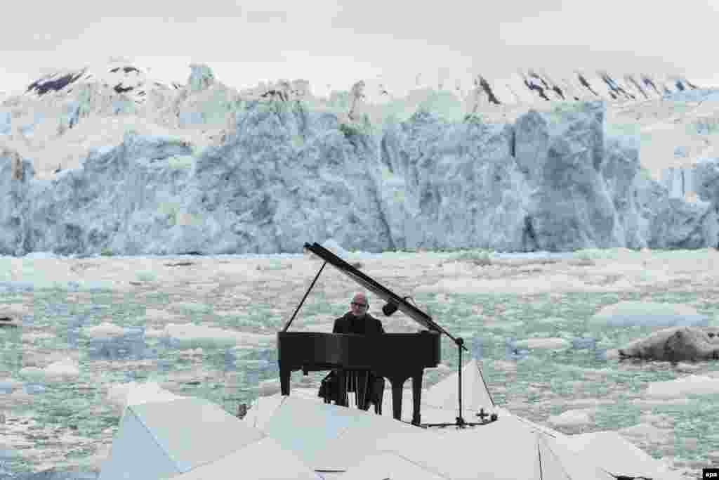 A handout image released by Greenpeace shows Italian pianist Ludovico Einaudi playing the piano during a concert in front of the Wahlenbergbreen glacier in Norway on June 20. (epa/Pedro Armestre)