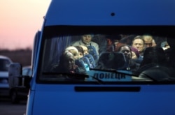 People wait in a bus to get through a checkpoint on a road linking Ukrainian government-controlled territory with a region controlled by Russia-backed separatists in Donetsk on March 13.