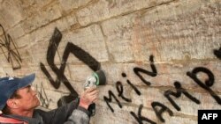 Рабочий стирает нацистский символ со стены Павловского дворца в Петербурге