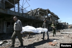 Men identified by local media as Ukrainian prisoners of war carry a stretcher with the remains of fallen soldiers at the city's airport in Donetsk on May 22. Mashonkin says he and his fellow prisoners were forced to do the same work.