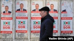 A man walks past election posters in Chisinau a day ahead of the February 24 Moldovan elections.