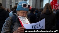 RUSSIA -- A demonstrator holds a book of Russian constitution and a poster that reads: "No raising of the retirement age", during a protest against the government's plans to raise the retirement age, in front of the Russian State Duma, in Moscow, Septembe