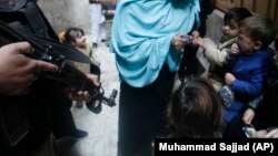 پخوانی تصویر: د پوليو يوه کارکوونکې د پولیسو په څار کې يو ماشوم ته تر ويکسينو وروسته په لاس نښه کوي.