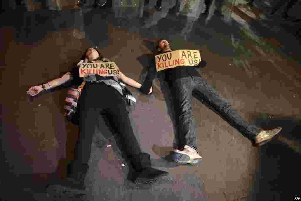 Cypriot protesters lie on the ground with signs during a demonstration against an EU bailout deal outside the parliament in the capital, Nicosia. (AFP/Yiannis Kourtoglou)