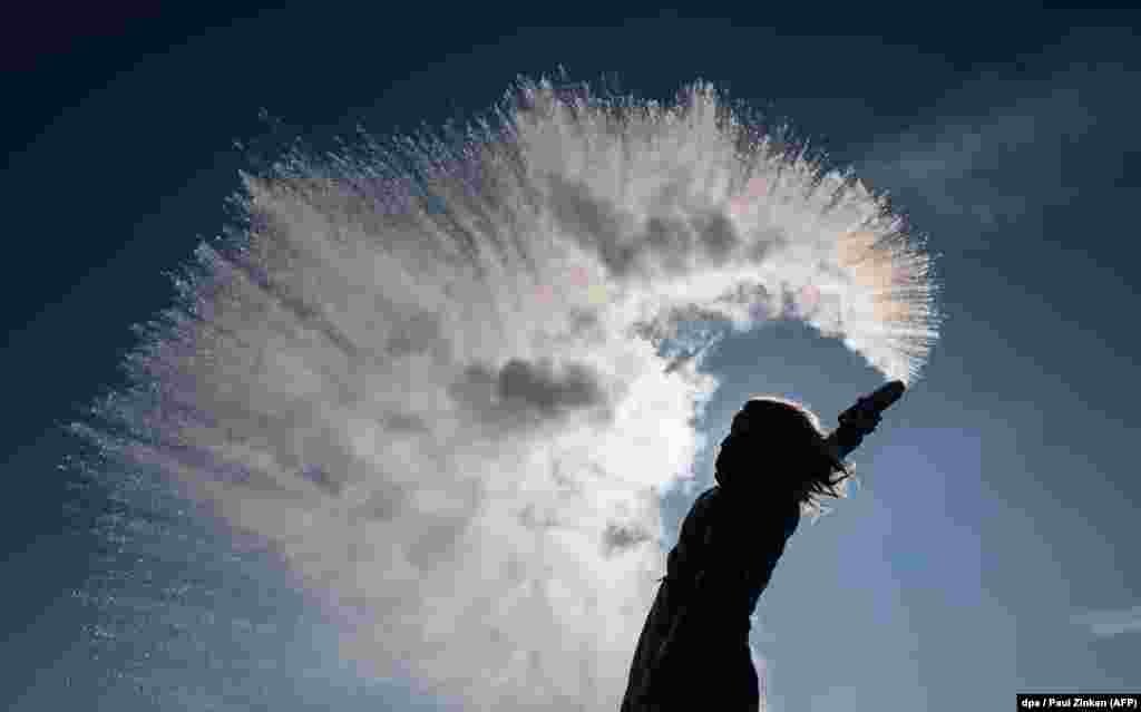 A woman tosses hot water into the freezing air in Berlin. The hot water is immediately turned into a sparkling cloud of snow. (AFP/dpa/Paul Zinken)