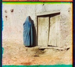 A woman in a burqa stands outside a residence in Samarkand.