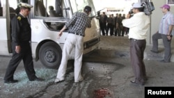 Syrian security personnel inspect the wreckage of a bus, after a bomb exploded in central Damascus on April 27.