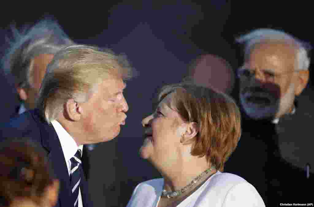 U.S. President Donald Trump kisses German Chancellor Angela Merkel during the G7 "family photo" in Biarritz, France. (AP/Christian Hartmann)
