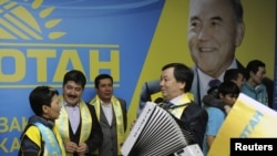 Члены партии "Нур Отан" отмечают победу на парламентских выборах на фоне портрета лидера партии и президента Казахстана Нурсултана Назарбаева. Астана, 16 января 2012 года.