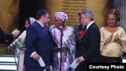 Actorul George Clooney (centru dreapta) și Ruben Vardanian îi acordă Premiul Aurora pentru trezirea umanității lui Marguerite Barankitse (centru), o lucrătoare umanitară din Burundi, la o ceremonie la Erevan, în aprilie 2016.